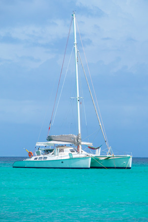 Beautiful view of a catamaran yacht anchored in a Caribbean bay, nobody on board, with French flagの写真素材