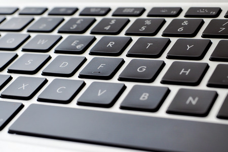 Closeup view of a modern notebook keyboard, black keys and silver alloy body