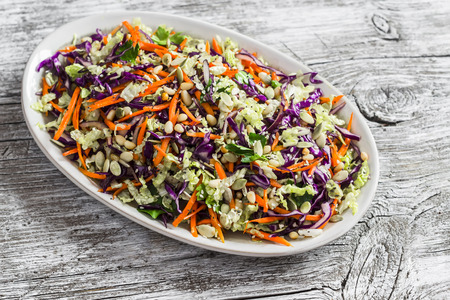 Fresh vegetable salad with red cabbage, carrots, sweet peppers, herbs and seeds. Healthy vegetarian food. On light  wooden rustic backgroundの写真素材