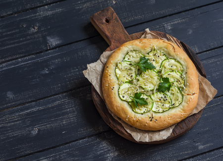 Vegan zucchini pizza on a rustic cutting board on dark wooden background. Healthy foodの写真素材