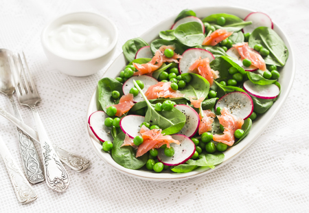 Smoked salmon, spinach, green pea and radish salad.  Delicious lunch. On a light backgroundの写真素材