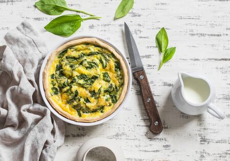 Pie with spinach, cheese and egg on a light wooden backgroundの写真素材