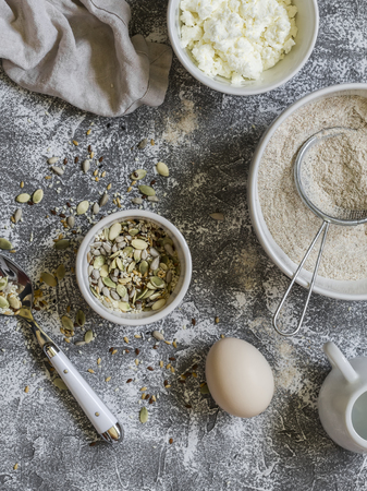 Ingredients for cooking whole grain multi seed bread - whole wheat flour, eggs, ricotta cheese, seeds, on a grey stone background. Baking backgroundの写真素材