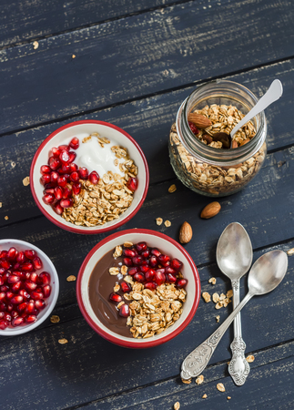 Healthy Breakfast - yogurt with homemade granola and pomegranate on a dark wooden boardの写真素材