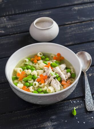 Chicken soup with vegetables and pasta on a dark wooden backgroundの写真素材