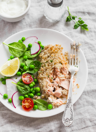 Baked salmon with lemon grain crust and fresh vegetable salad with peas, spinach, radishes and cherry tomatoes. Delicious healthy dinnerの写真素材