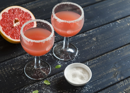 Fresh grapefruit juice in glass beakers on dark wooden surfaceの写真素材