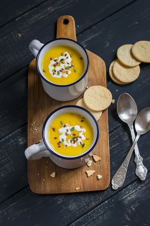 pumpkin soup in ceramic mugs on a wooden surface - healthy foodの写真素材