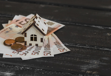 Model house and Euro banknotes on dark wooden background. The concept of buying, selling, trading,...