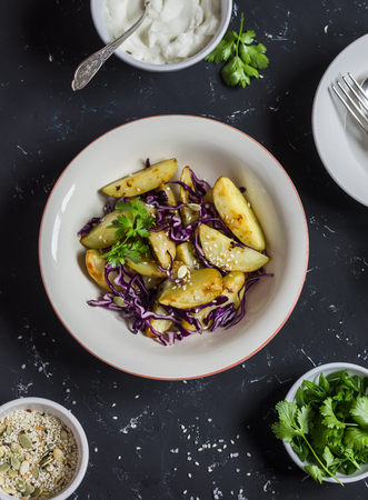Baked potatoes and red cabbage salad on dark stone background. Healthy vegetarian lunch or snack. Top viewの写真素材