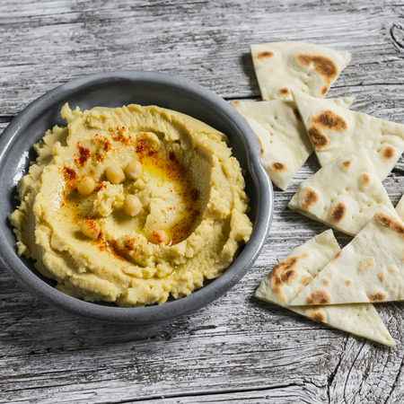 hummus in a ceramic plate on a light wooden surfaceの写真素材