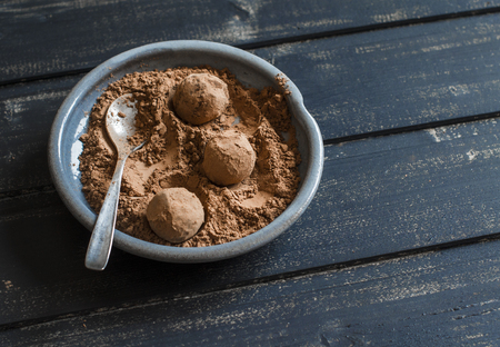 Homemade dark chocolate truffles on vintage ceramic plate on dark wooden surfaceの写真素材