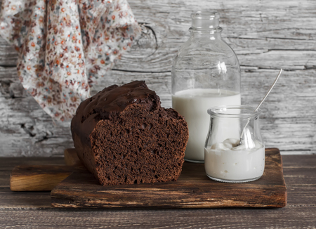 Chocolate cake, milk bottle, yogurt on rustic wooden backgroundの写真素材