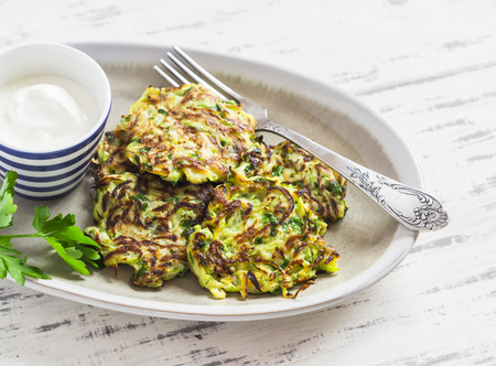 Zucchini fritters with herbs on a ceramic plate on a light wooden background. Healthy, vegetarian foodの写真素材
