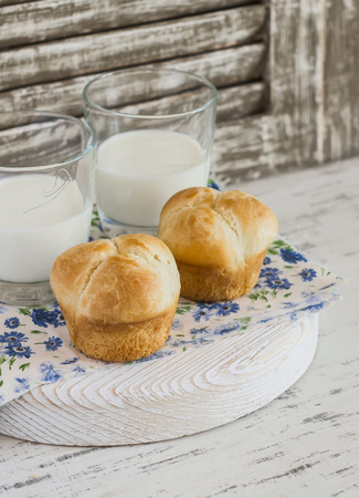 Homemade brioche bun and two glasses of milk on a light rustic wood backgroundの写真素材