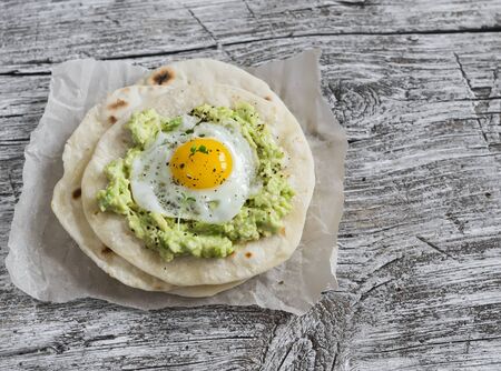 Homemade tortilla with mashed avocado and a fried quail egg. Delicious snack, healthy foodの写真素材