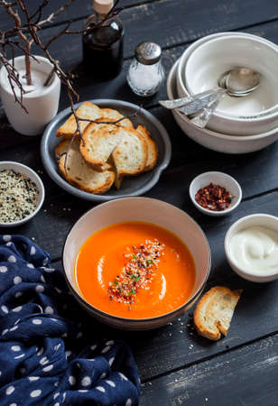 Roasted pumpkin soup in a ceramic bowl on dark wooden surfaceの写真素材
