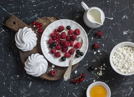 Raspberry, black currant, cheese, cream, honey, meringue - tasty breakfast or snack. On a dark backgroundの写真素材