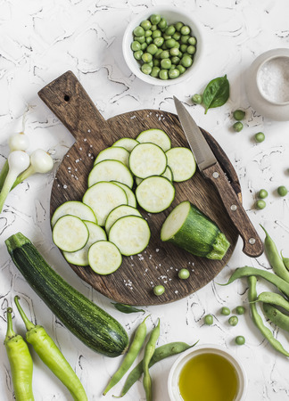 Cut zucchini on rustic cutting board, peppers, green beans on a white background. Raw ingredients. Cooking backgroundの写真素材