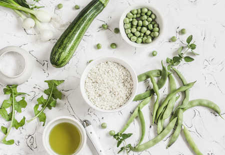 Raw ingredients - rice, zucchini, green beans and peas, olive oil on a light background. Cooking background. Healthy vegetarian foodの写真素材