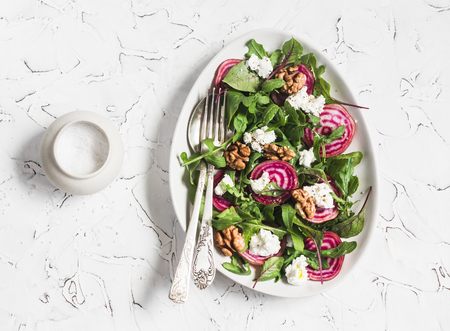 Beets salad with  arugula, feta cheese and walnuts. On a light background, top viewの写真素材
