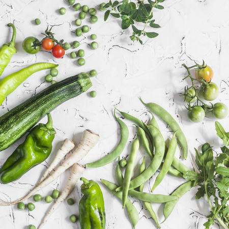 Fresh raw green vegetables - zucchini, green peas and beans, parsnips, peppers, tomatoes, onions on a white background. Healthy  Vegetarian, vegan tableの写真素材