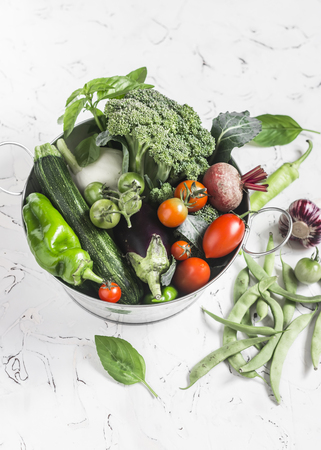 Fresh vegetables - broccoli, zucchini, beets, peppers, tomatoes, green beans, garlic, basil in a metal basket on a light background. Healthy foodの写真素材