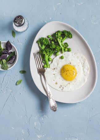 Fried egg and broccoli. Healthy breakfast or snack. On a light blue background, top viewの写真素材