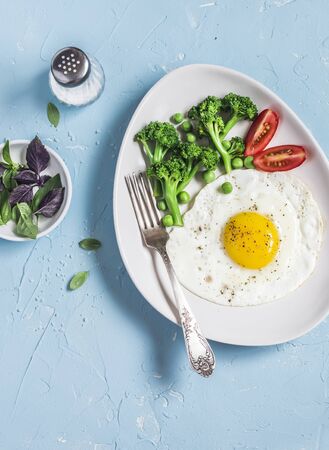 Fried egg and broccoli. Healthy breakfast or snack. On a light blue background, top viewの写真素材