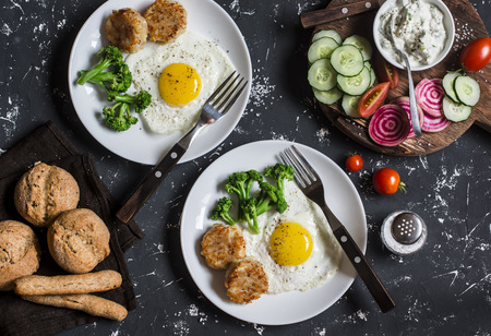 Fried eggs, chicken meatballs, vegetables, and yogurt sauce on a dark background. Healthy lunch or snackの写真素材