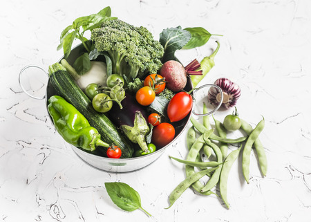 Fresh vegetables - broccoli, zucchini, beets, peppers, tomatoes, green beans, garlic, basil in a metal basket on a light background. Healthy foodの写真素材