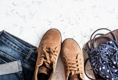 Women's clothing and accessories - suede boots, jeans, leather bag, scarf. On a light background, top viewの写真素材