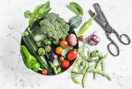 Fresh vegetables - broccoli, zucchini, beets, peppers, tomatoes, green beans, garlic, basil in a metal basket on a light background. Healthy foodの写真素材