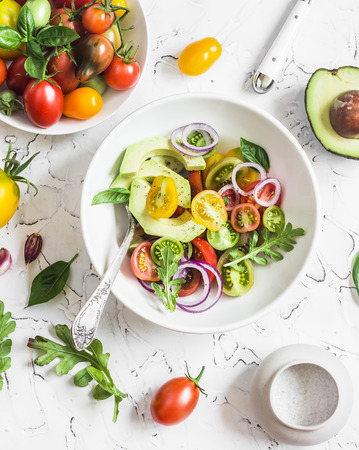 Fresh salad with tomatoes and avocado on a light background. Top viewの写真素材