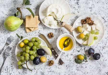 Snack table - goat cheese, grapes, pears, plums, nuts, honey, cracker. Top viewの写真素材