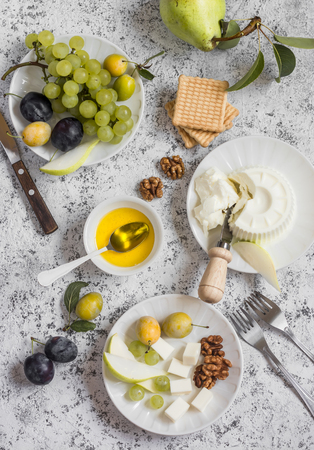 Snack table - goat cheese, grapes, pears, plums, nuts, honey, cracker. Top viewの写真素材