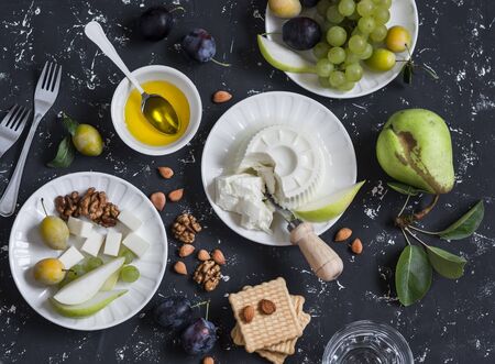 Snack table - goat cheese, grapes, pears, plums, nuts, honey, cracker. Top viewの写真素材