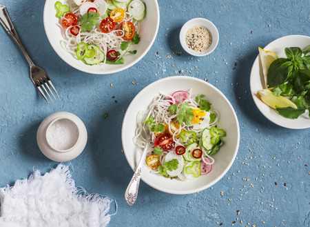 Rice noodles and vegetables salad. Healthy vegetarian food. On a blue background, top viewの写真素材