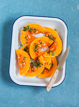 Raw chopped pumpkin in a baking dish on a blue background. Healthy vegetarian foodの写真素材