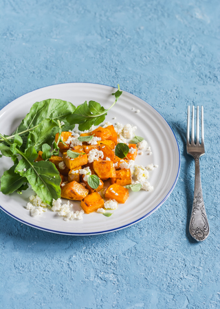 Baked pumpkin and goat cheese salad on a blue background. Healthy foodの写真素材