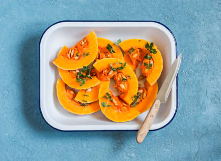 Raw chopped pumpkin in a baking dish on a blue background. Healthy vegetarian foodの写真素材