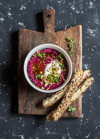 Healthy vegetarian beet hummus and puff pastry bread sticks on a wooden rustic board on a dark backgroundの写真素材