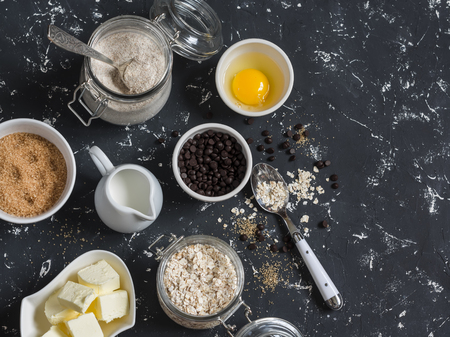 Baking background. Flour, sugar, butter, rolled oats, eggs, chocolate chips on a dark background. Baking ingredientsの写真素材