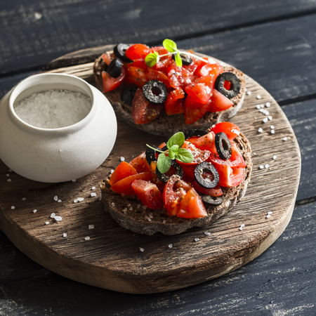 Tomatoes and olives bruschetta on dark rustic wooden backgroundの写真素材