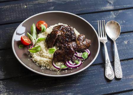 Grilled chicken liver, couscous and fresh vegetable salad on a dark wooden backgroundの写真素材