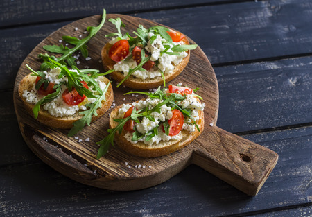 Sandwiches with cheese, tomatoes and arugula on a rustic wooden board. Healthy foodの写真素材