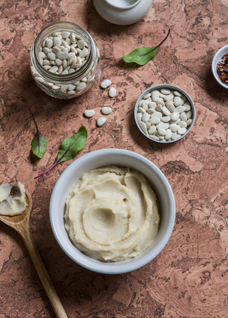 Bean puree in a ceramic bowl, jar with raw beans on a stone background. Top viewの写真素材