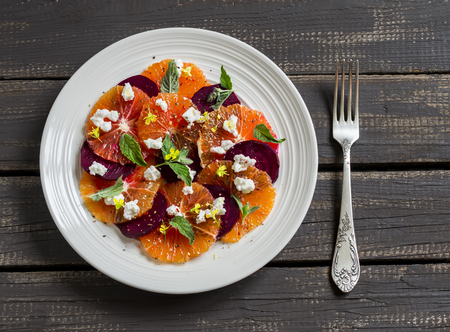 salad with beets, oranges and soft cheese on a white plate on a dark wooden backgroundの写真素材