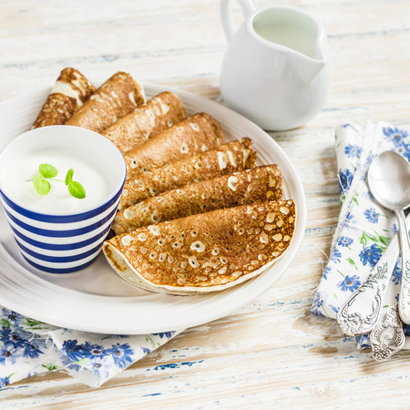 Pancakes and natural yoghurt - delicious breakfast. On a light rustic wood background, vintage and rustic styleの写真素材