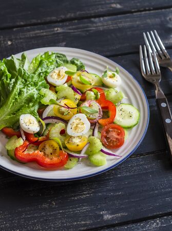 Fresh salad with cherry tomatoes, cucumbers, sweet peppers, celery and quail eggs. Healthy tasty foodの写真素材